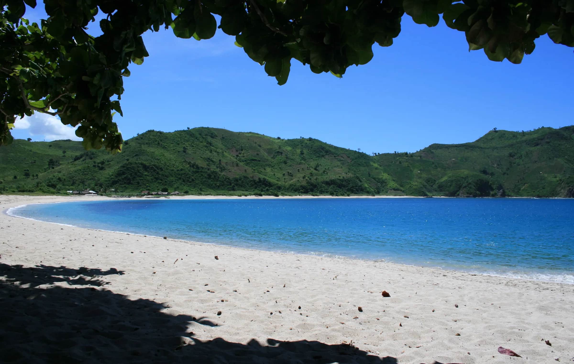 Baie de Mawun près de Kuta Lombok : plage de sable blanc, lagon bleu et collines vertes au sud de Lombok