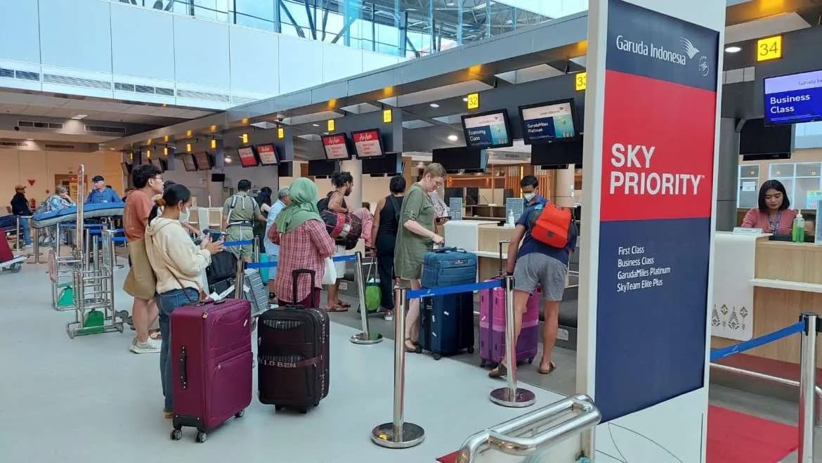 Comptoirs d'enregistrement Garuda Indonesia dans le hall de l'aéroport international de Lombok, avec des voyageurs et leurs valises