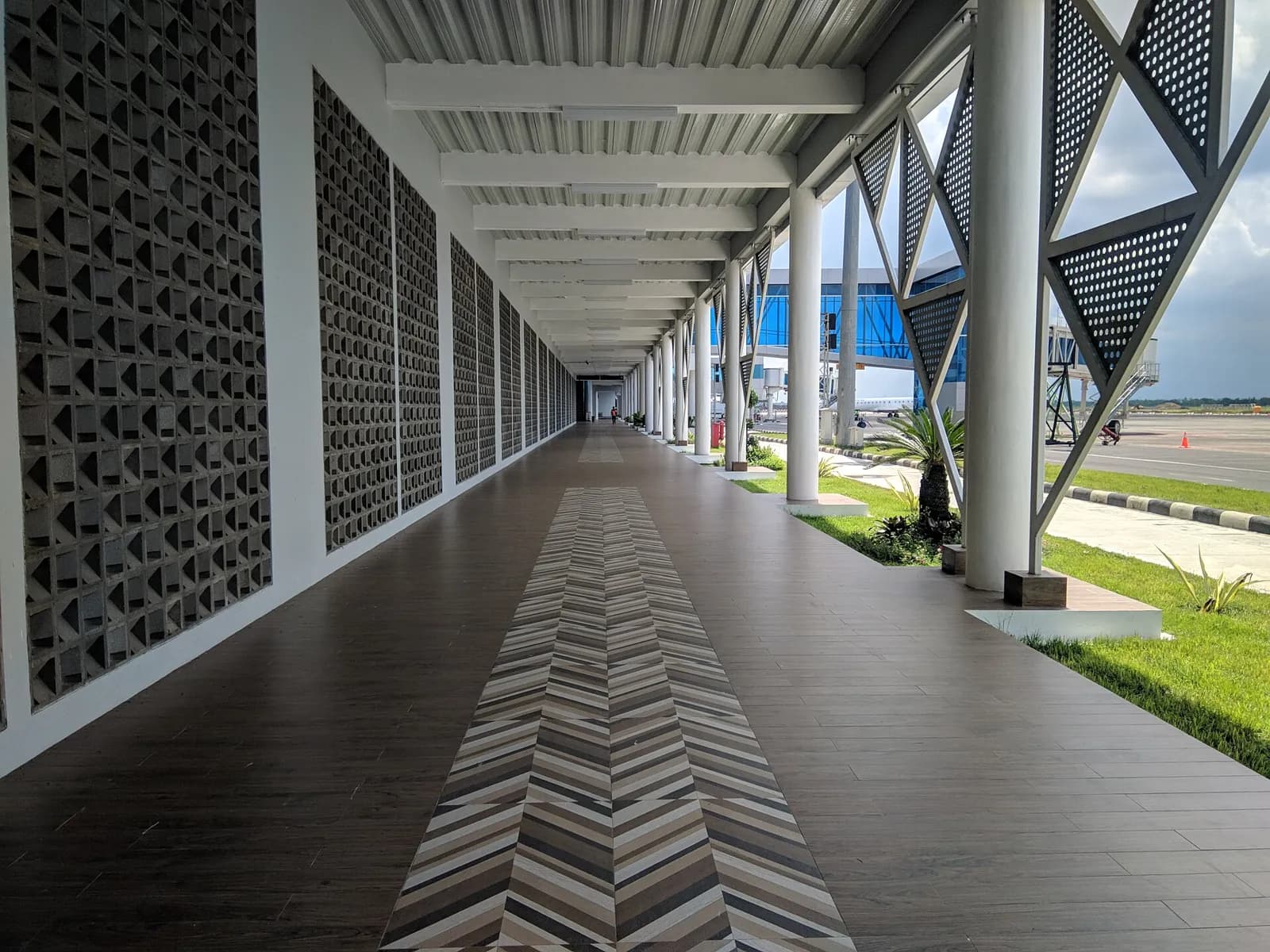 Galerie couverte à claire-voie reliant les passerelles d'embarquement au terminal d'arrivée de l'aéroport de Lombok