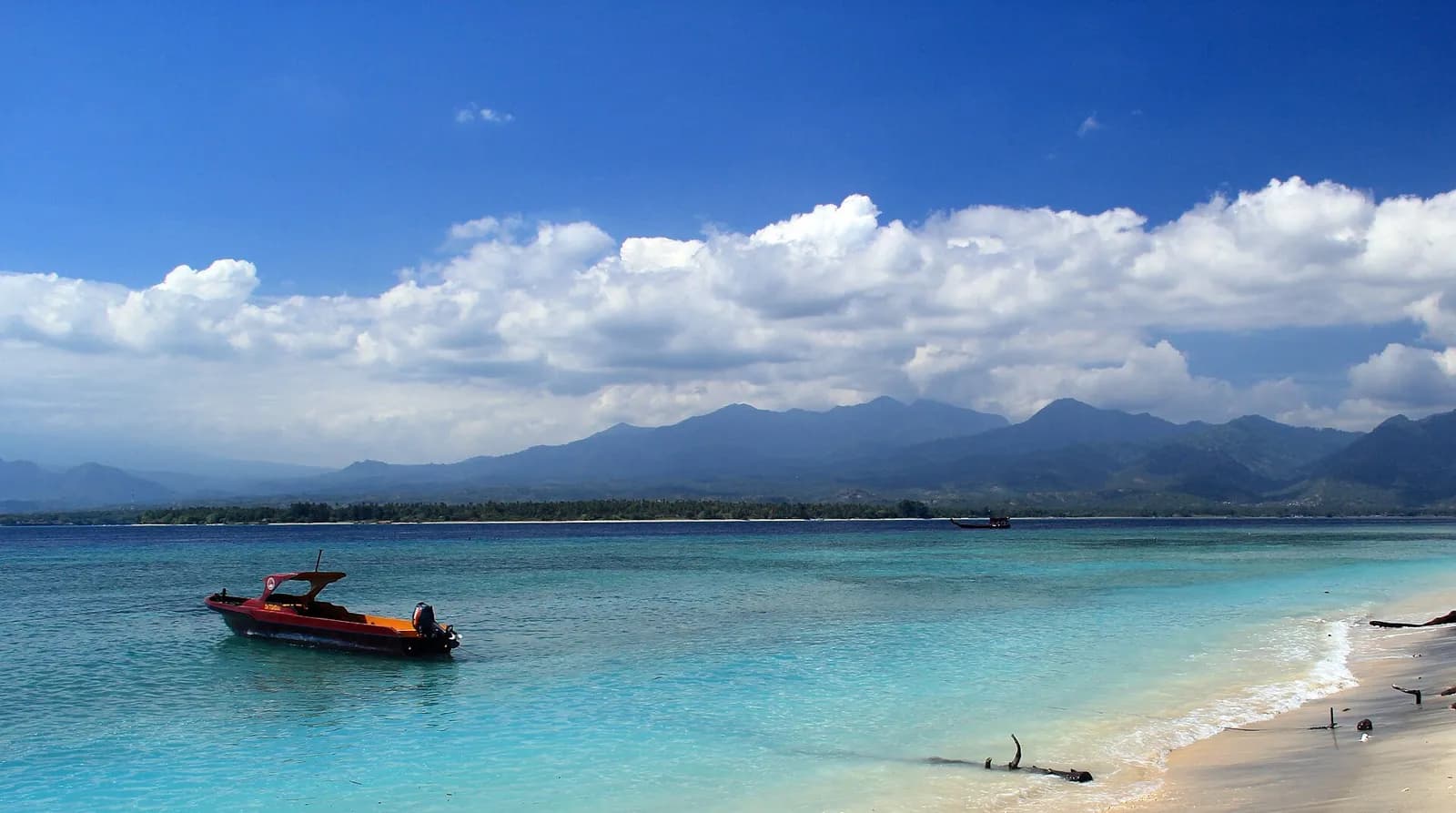 Plage de la côte est de Gili Air avec un bateau rapide, et les montagnes de Lombok au fond