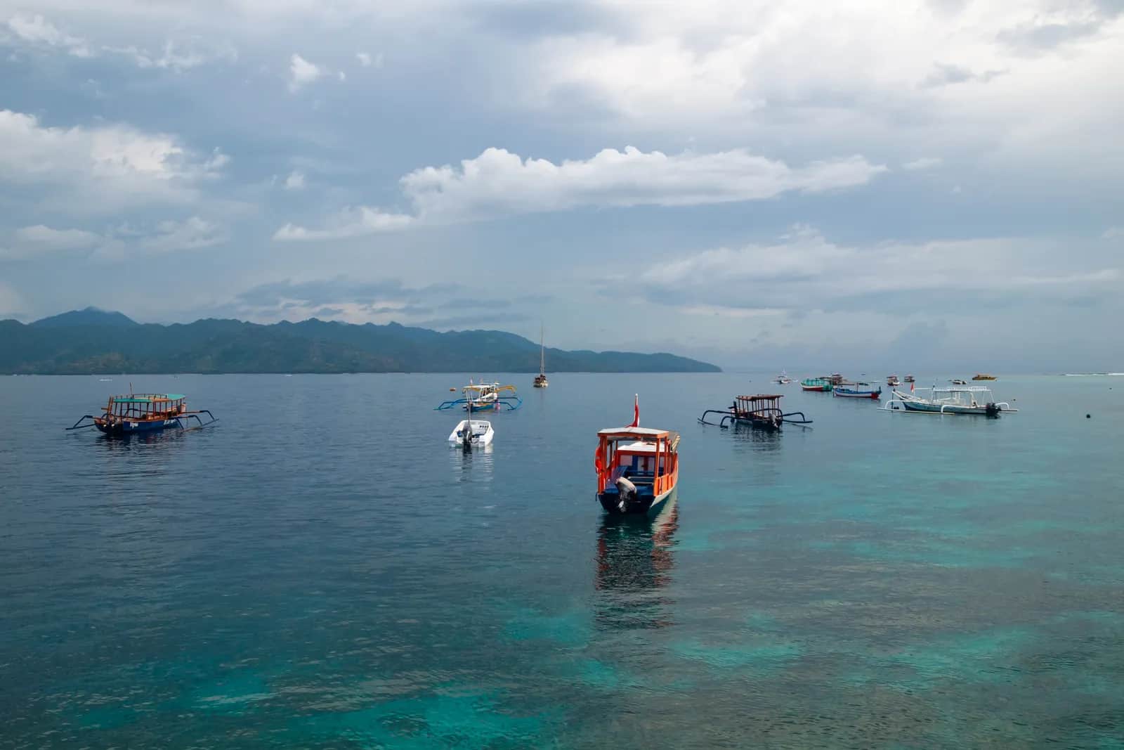 Bateaux locaux et bateaux touristiques dans le détroit de Lombok, au large des îles Gili, avec la côte de Lombok au fond