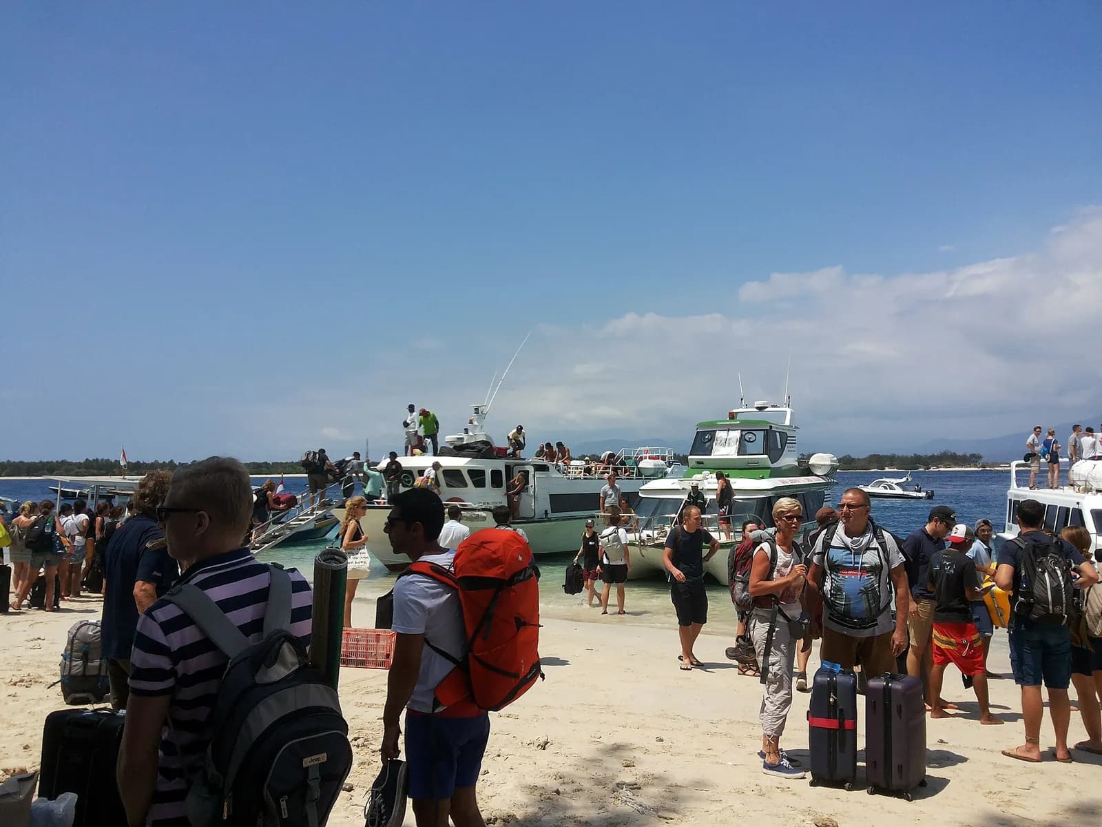 Voyageurs avec leurs sacs à dos débarquant de fast boats sur une plage de Gili Trawangan