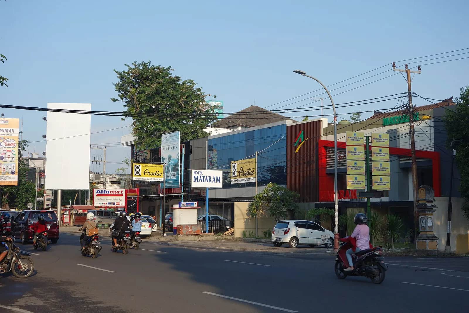 Rue commerçante de Mataram, sur l'île de Lombok, avec scooters, minimarché et hôtel