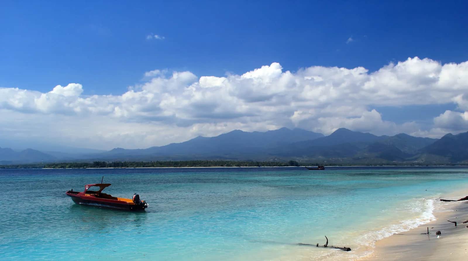 Côte est de Gili Air, eau turquoise, bateau et montagnes de Lombok au fond