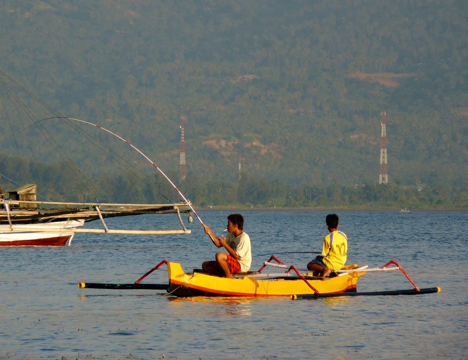 Deux pêcheurs sur une pirogue à balancier jaune près du port de Gili Air