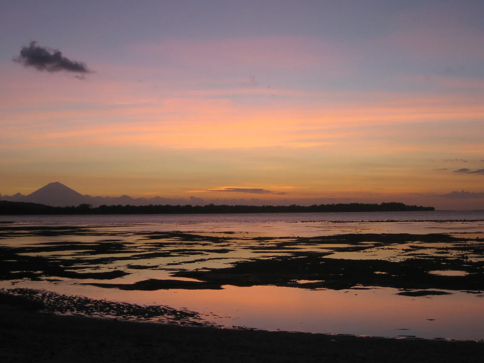 Coucher de soleil sur la mer à marée basse, avec la silhouette du mont Agung de Bali au fond, vu de Gili Air