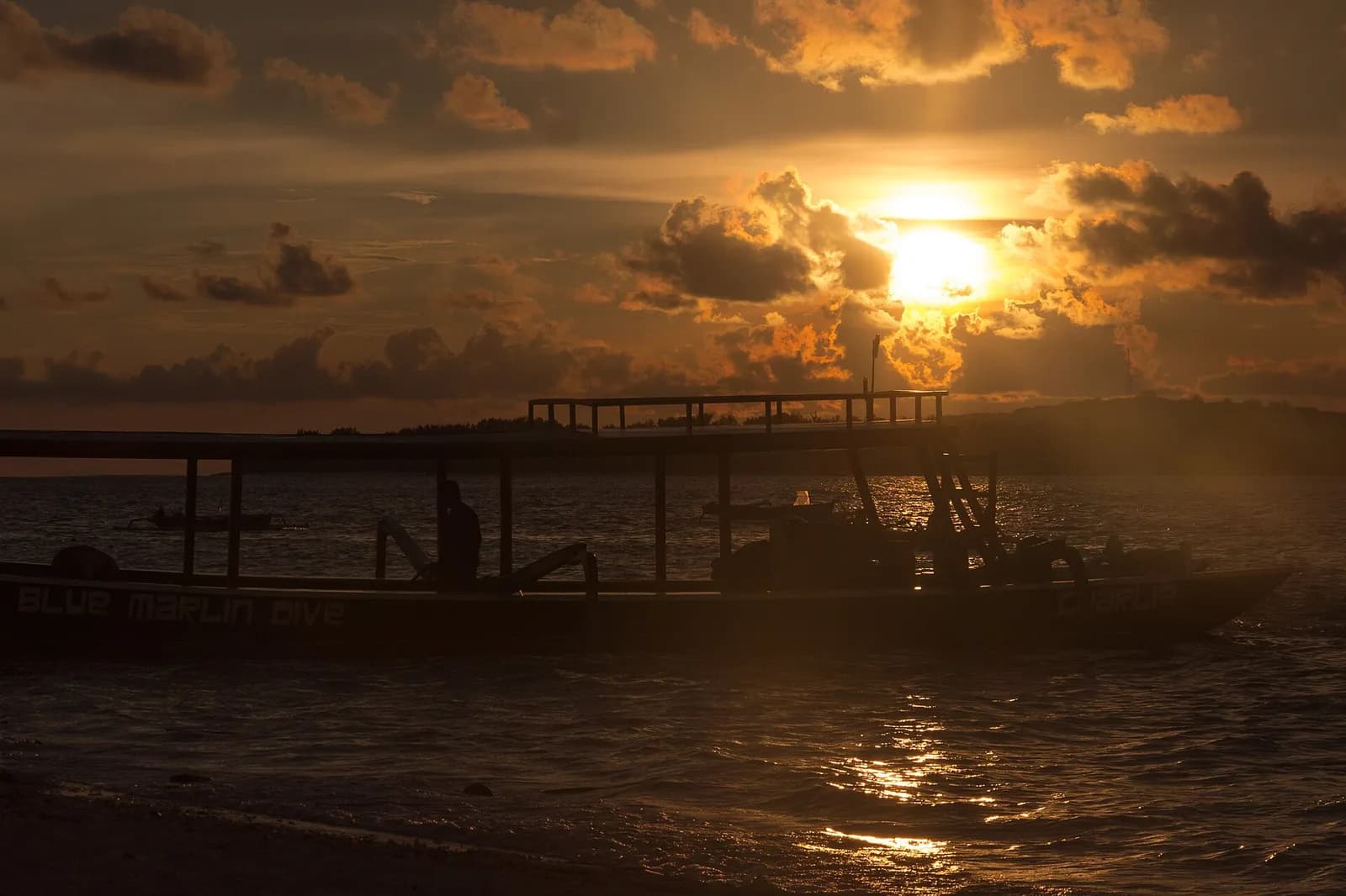 Bateau de plongée en contre-jour sur la plage de Gili Air au coucher du soleil