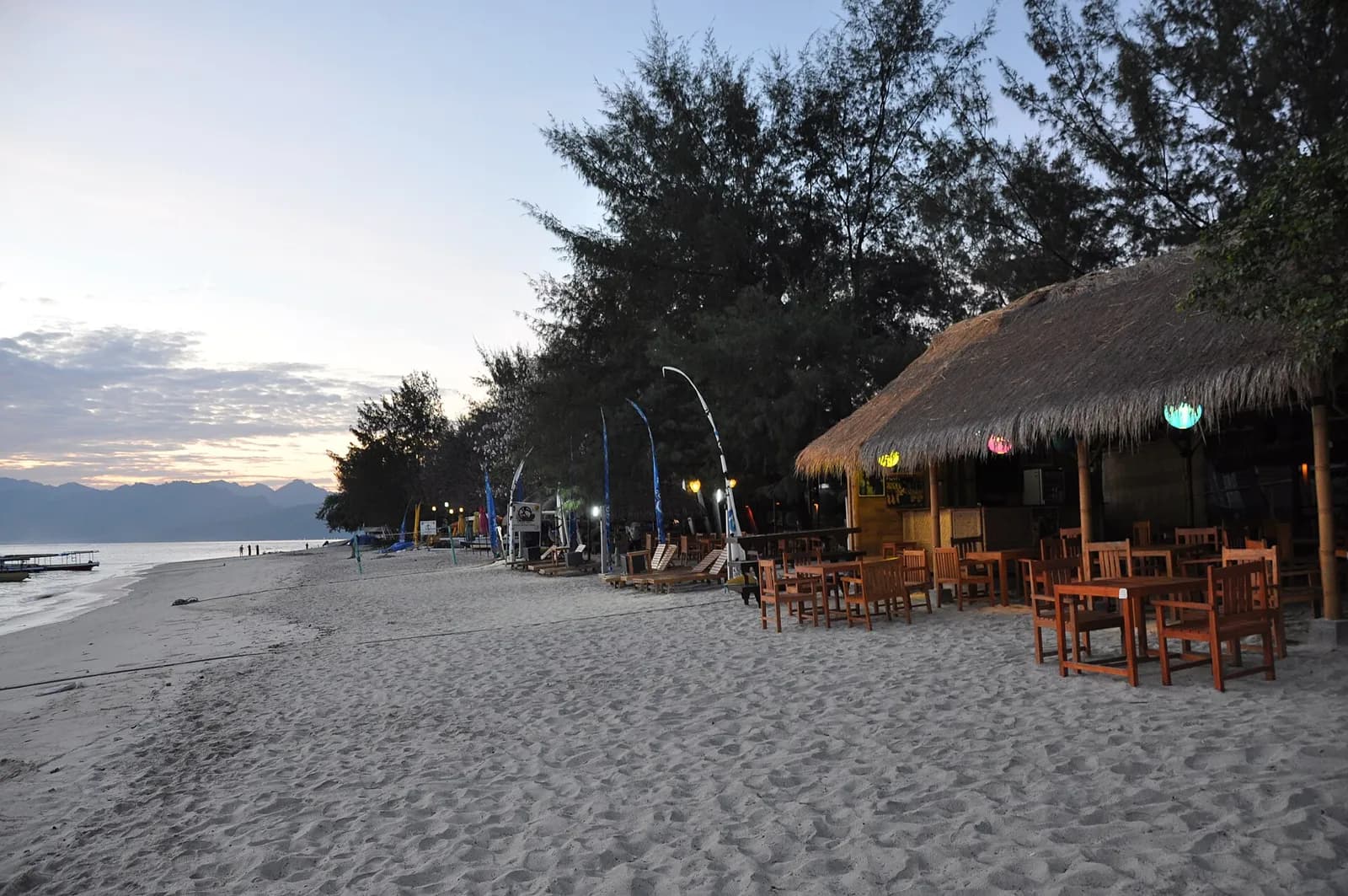 Plage de sable blanc et restaurant à toit de chaume au crépuscule sur Gili Trawangan, aux îles Gili