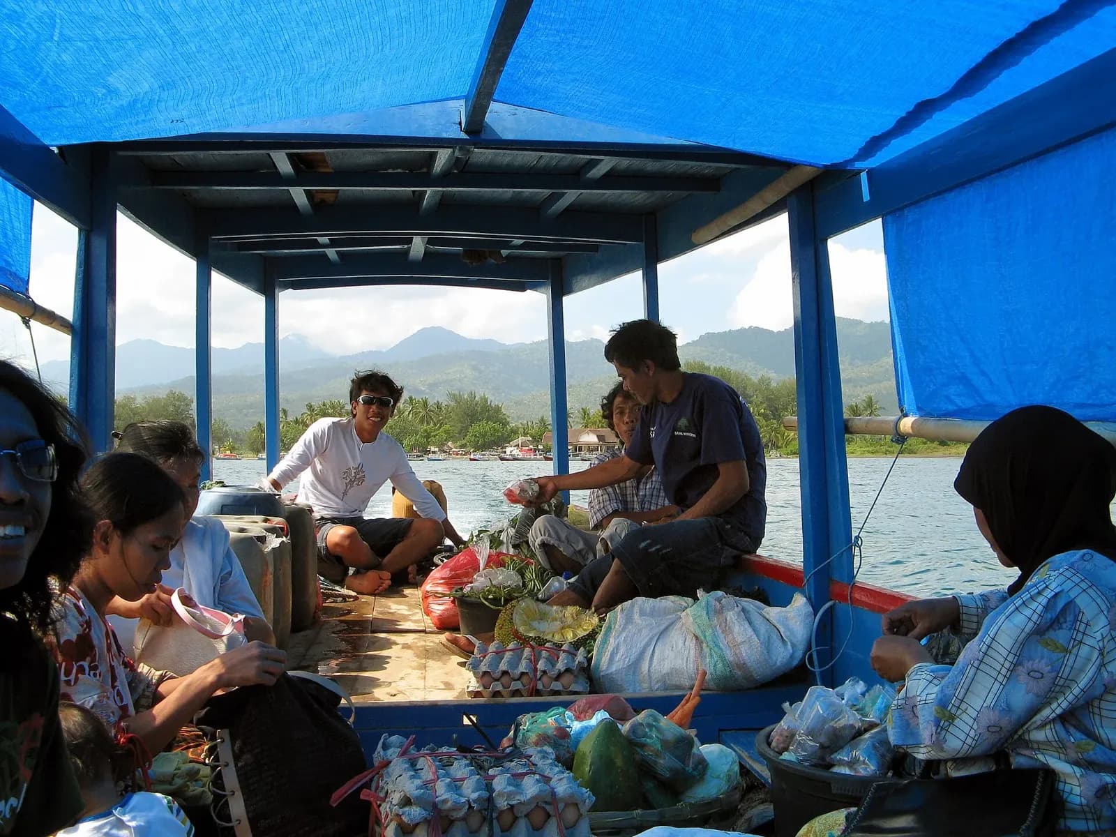 Intérieur d'un bateau public à toit bleu avec des passagers et leurs paquets, en route vers Gili Meno