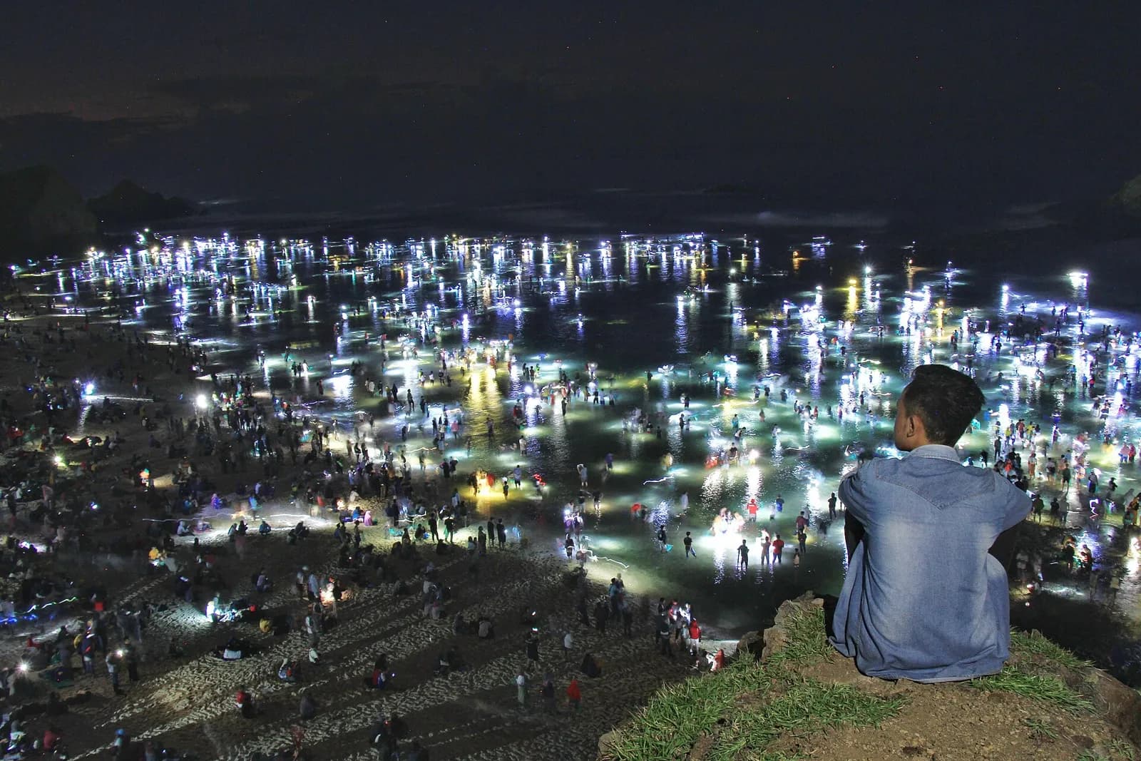 Foule de chercheurs de nyale avec des lampes sur l'estran la nuit, pendant Bau Nyale à Mandalika, Lombok