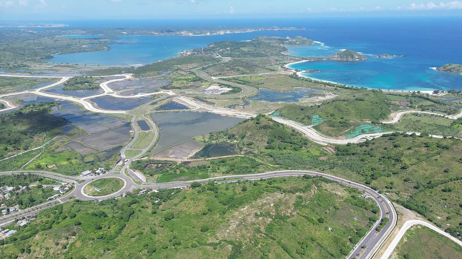 Vue aérienne de la zone de Mandalika, sur la côte sud de Lombok : routes, baie turquoise et collines vertes