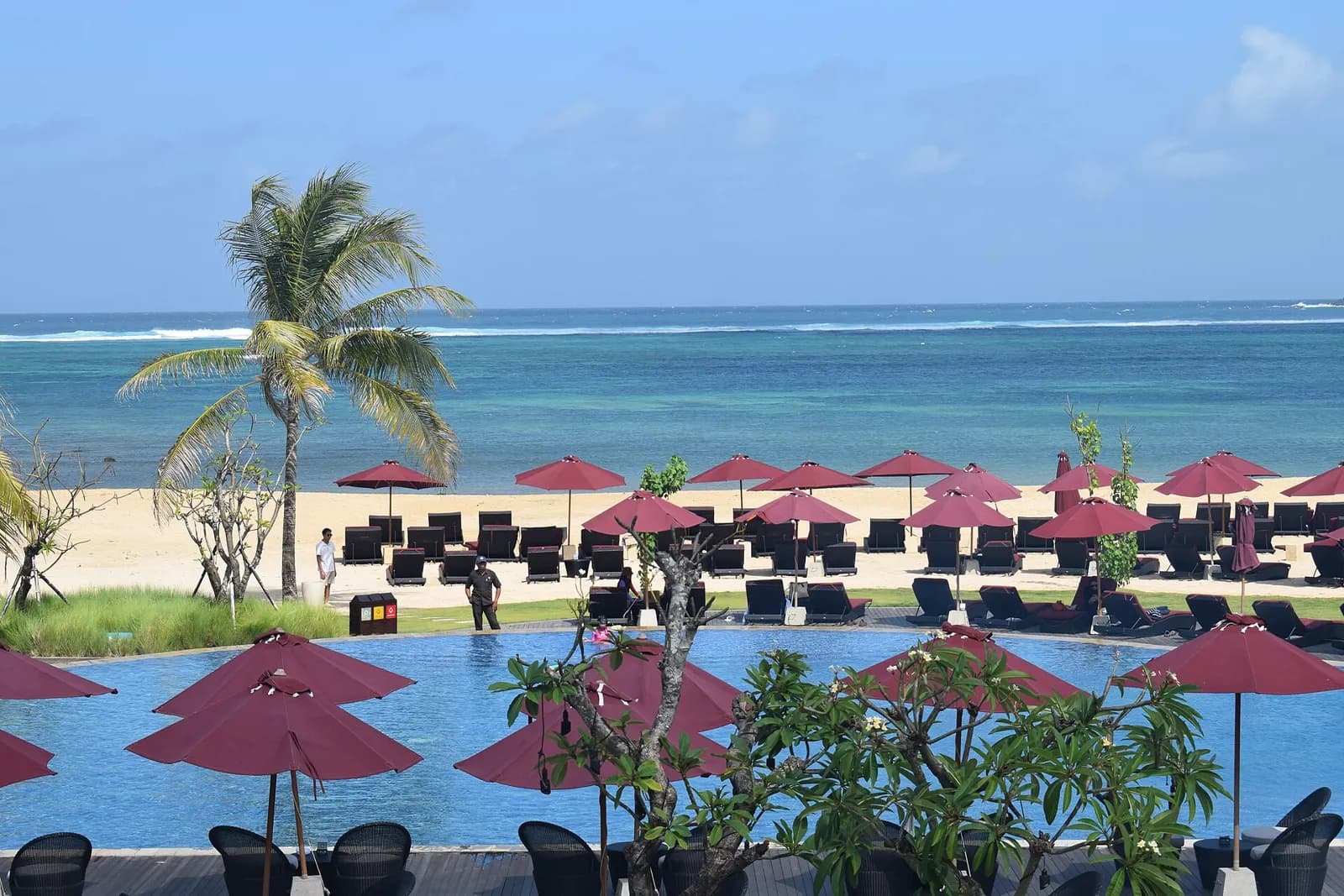 Plage de Mandalika vue depuis le Pullman Lombok Mandalika Beach Resort, avec piscine et parasols rouges