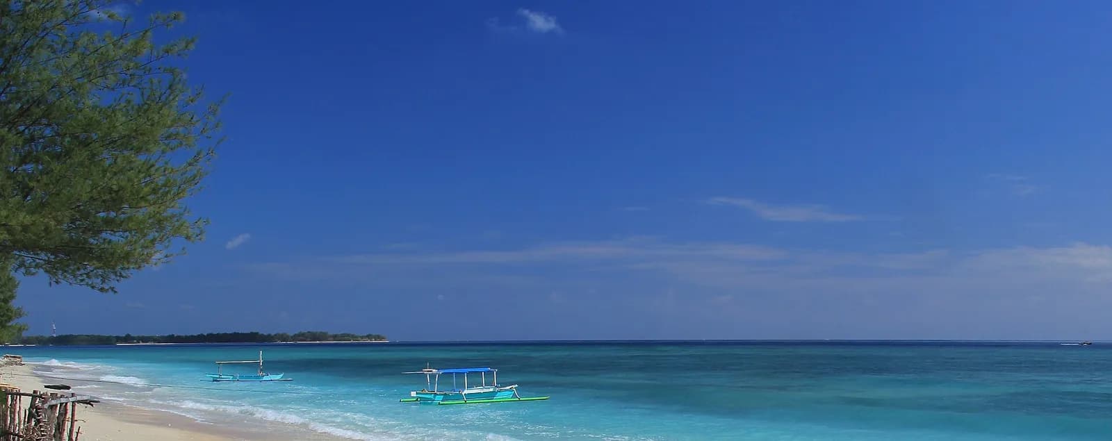 Pirogues à balancier sur une eau turquoise devant la plage de Gili Air, au nord-ouest de Lombok