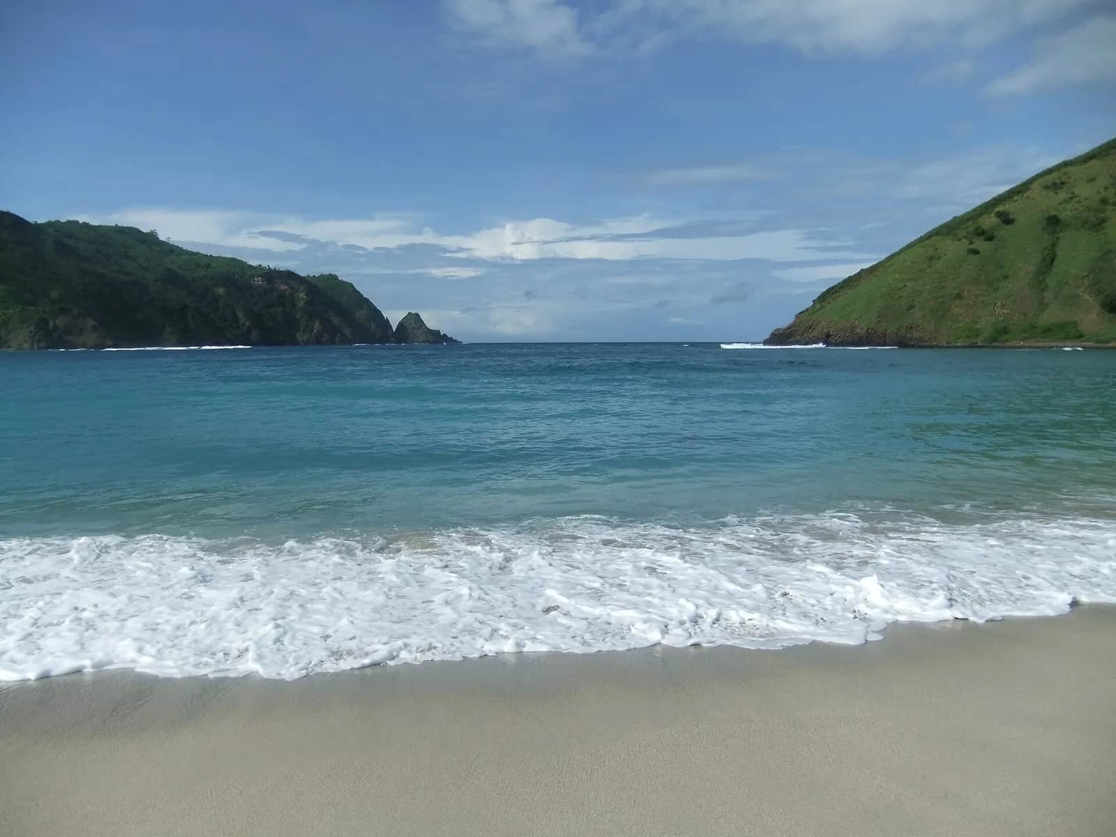 La baie de Mawun, au sud de Lombok, entre deux caps verts, avec une eau turquoise et du sable clair