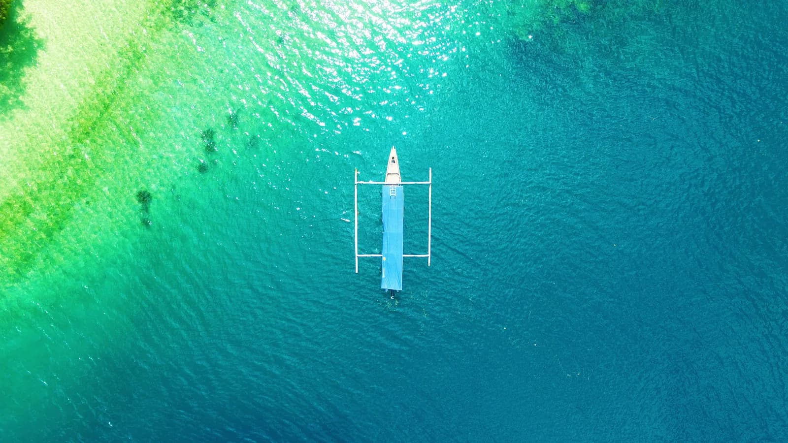Pirogue à balancier vue du ciel sur les eaux turquoise de Lombok