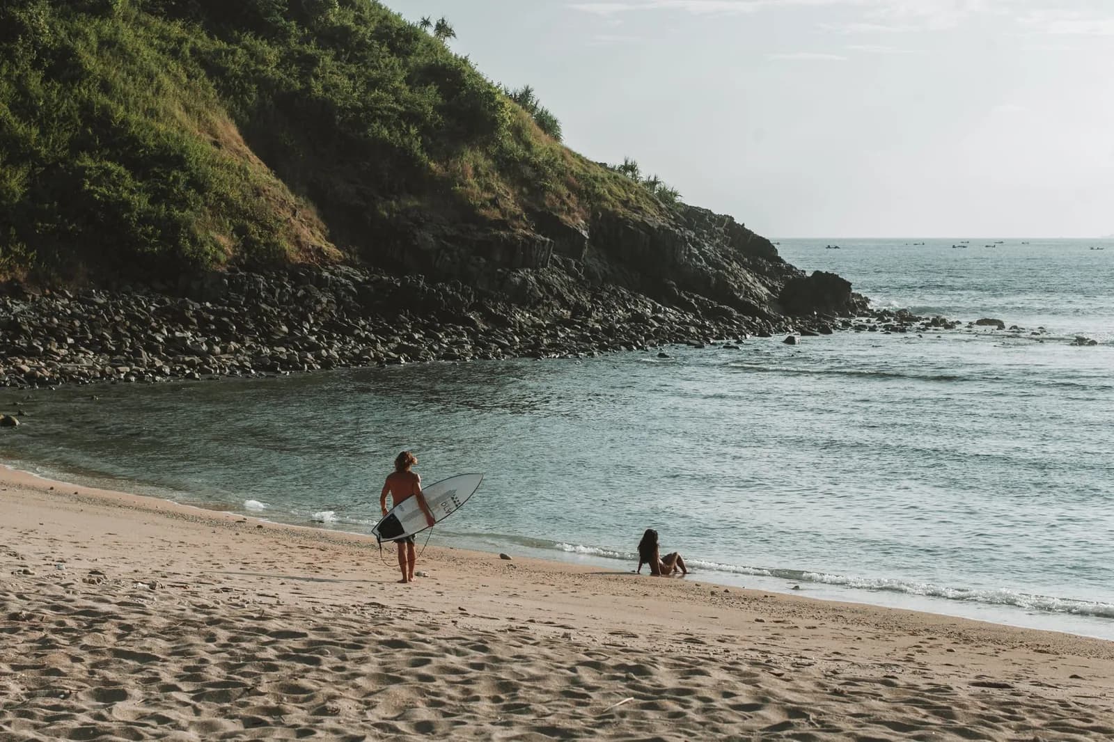 Surfeur marchant sur une plage de sable du sud de Lombok au lever du soleil