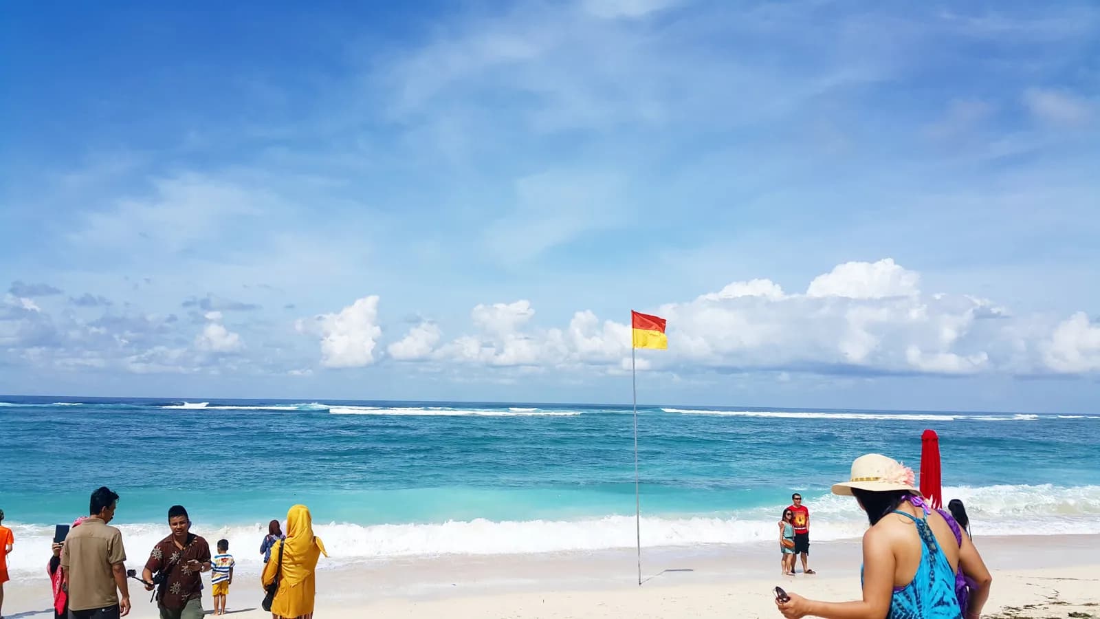 Baigneurs et drapeau de surveillance sur une plage de sable blanc de Gili Trawangan