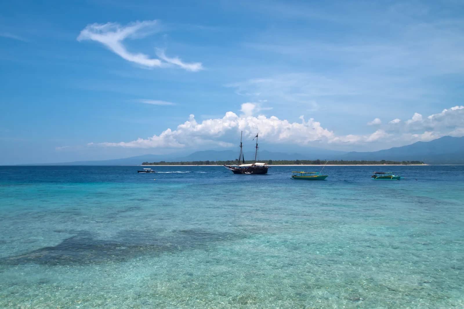 Eau turquoise et voiliers devant Gili Air, vue depuis Gili Meno, avec les montagnes de Lombok au fond