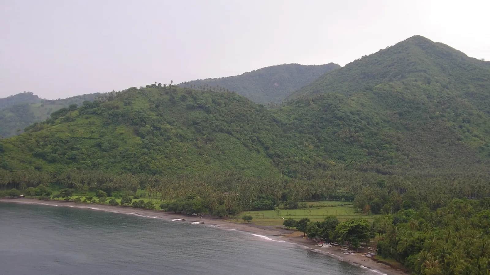 Baie de Senggigi, sur la côte ouest de Lombok, entre collines vertes et plage de sable sombre